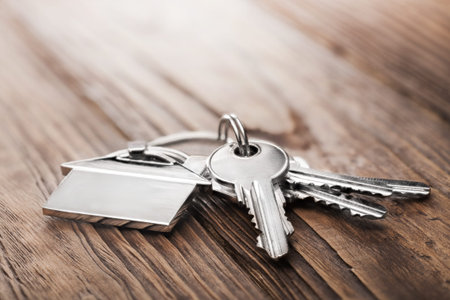 Estate concept, keychain with house symbol, key on wooden background