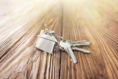 estate concept, keychain with house symbol, key on wooden backgroundの写真素材