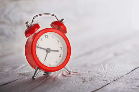 Concept of time, red clock on light wooden backgroundの写真素材