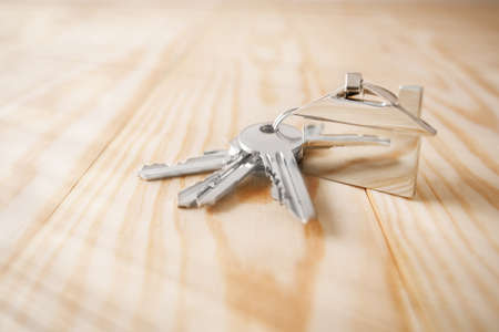 estate concept, keychain with house symbol, key on wooden backgroundの写真素材