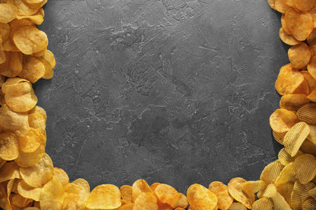 Pile of crispy potato chips lying  on an old concrete table in kitchen. Concept of fast food...