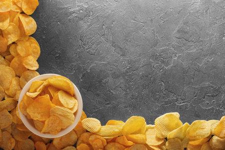 Pile of crispy potato chips lying  on an old concrete table in kitchen. Concept of fast food background. Free place for text, top view.の写真素材