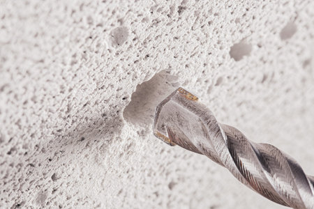 metal drill bit make holes in concrete wall on industrial drilling machine with shavings. Metal work...