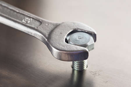 Wrench tightens  bolt in steel billet. Spanner, bolt, screw and nuts.の写真素材