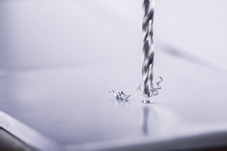 metal drill bit make holes in aluminum billet on industrial drilling machine with shavings. Metal...