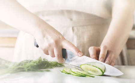 Chef slicing vegetables and cucumber on the table in restaurant. Process of cutting and preparation food in kitchen.の写真素材