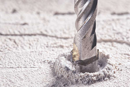 metal drill bit make holes in concrete wall on industrial drilling machine with shavings. Metal work industryの写真素材