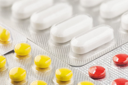 pile of medical pills in red, blue colors in silver plastic packaging