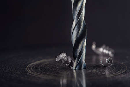 metal drill bit make holes in steel billet on industrial drilling machine with shavings. Metal work industry. multi cutting tool and end mill.の写真素材