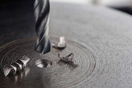 metal drill bit make holes in steel billet on industrial drilling machine. Metal work industry. multi cutting tool and end mill.の写真素材