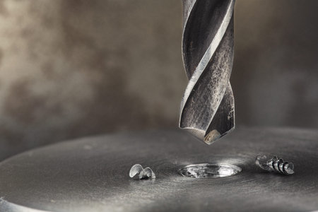 metal drill bit make holes in steel billet on industrial drilling machine. Metal work industry and...