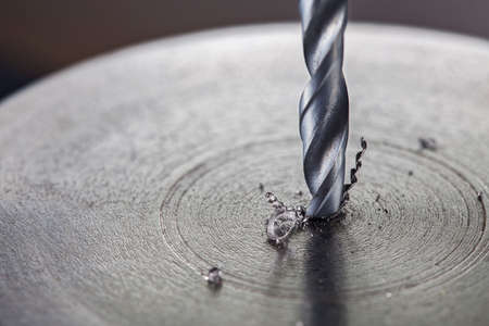 metal drill bit make holes in steel billet on industrial drilling machine. Metal work industry. multi cutting tool and end mill.の写真素材