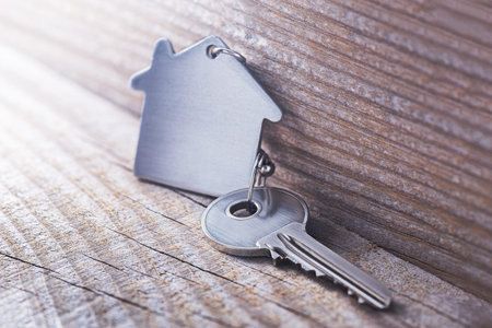 estate concept with symbol of house, key on wooden background