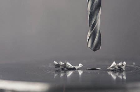 metal drill bit make holes in steel billet with lubricating liquid on industrial drilling machine. Metal work industry and locksmith work.の写真素材