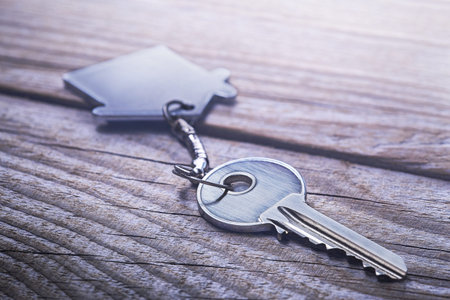 estate concept with symbol of house, key on wooden background