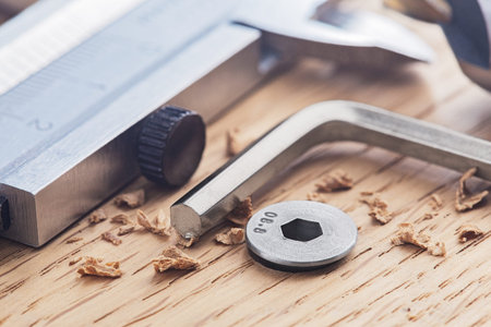 hex bolt screw by hex wrench in wooden oaks plate with with vernier caliper and ruler