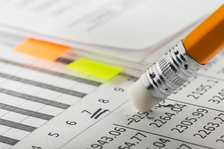 Accounting document with eraser erases blots in the document and checking financial chart. Concept of banking, financial report and financial audit.の写真素材