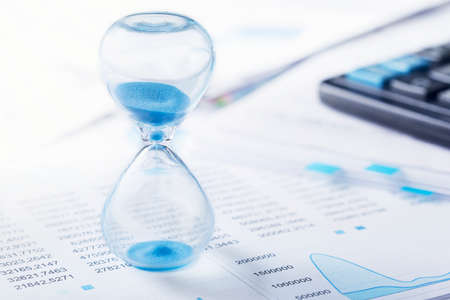 Hourglass, financial charts and calculator. Sandglass and best time for investment.の写真素材