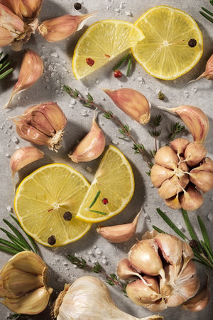 Garlic, rosemary, lemon on gray background. Spices, herbs, parsley, top view.の写真素材