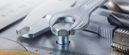 Wrench tightens bolt in steel billet. Spanner, bolt, screw and nuts.