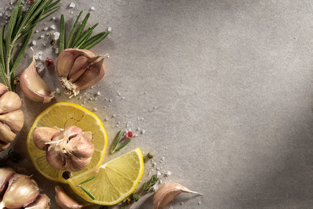 Garlic, rosemary, lemon on gray background. Spices, herbs, parsley, top view.の写真素材