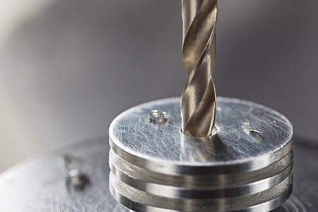 metal drill bit make holes in aluminum radiator on industrial drilling machine. metal work industry.