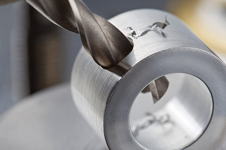 metal drill bit make holes in aluminum pipe on industrial drilling machine. metal work industry.