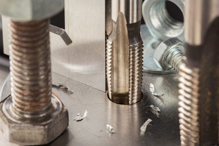 Thread tap drill steel billet with drill bit on background. working cutter.