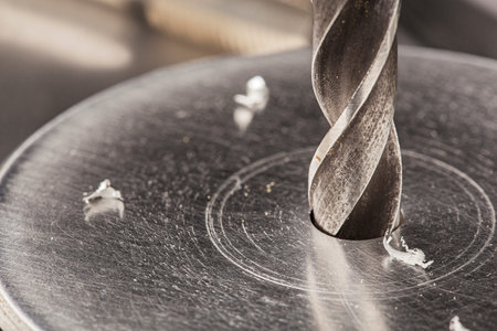 metal drill bit make holes in aluminum billet on industrial drilling machine with shavings. metal...