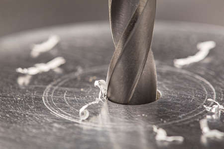 metal drill bit make holes in aluminum billet on industrial drilling machine with shavings. metal work industry. multi cutting tool and end mill.の写真素材