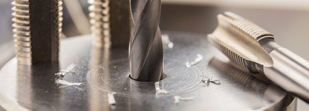 metal drill bit make holes in aluminum billet on industrial drilling machine with shavings. metal...