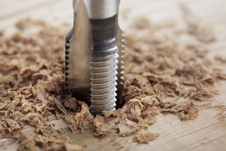 Thread tap drill cutting hole in wooden plate. working cutter.の写真素材