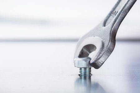 Wrench tightens bolt in steel billet. Spanner, bolt, screw and nuts.の写真素材