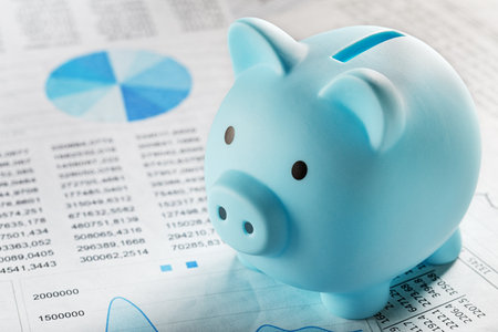 Moneybox for money on the background of documents and financial charts. Investment and capital accumulation conceptの写真素材