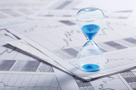 Best time for investment. Hourglass, financial charts and calculator.