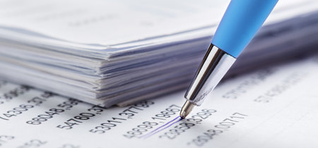 Accounting document with pen, money, coins and checking financial chart. Concept of banking, financial report and financial audit.の写真素材