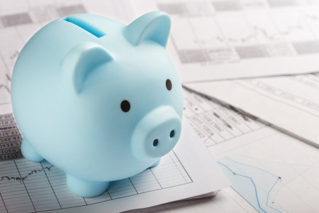 Moneybox for money on the background of documents and financial charts. Investment and capital accumulation conceptの写真素材