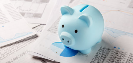 Moneybox for money on the background of documents and financial charts. Investment and capital accumulation conceptの写真素材