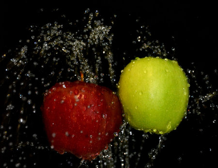 two apples red and green in water on a black backgroundの写真素材