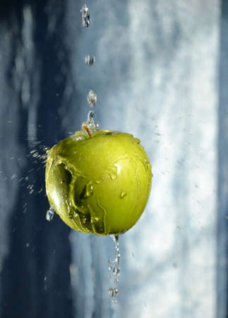 green apple with drop of water on turn blue backgroundの写真素材
