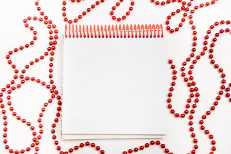 notepad with a place for text on a white background with red Christmas decorationsの写真素材