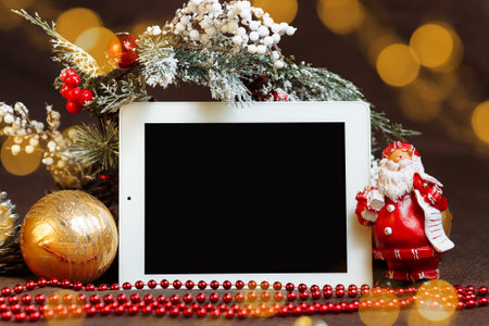 horizontal tablet with a blank screen among Christmas decorations highlights and santa Claus mock up