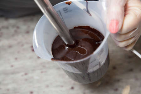 chef pastry whisk blender chocolate frosting in order to let the air out of icing for chocolate cakeの写真素材