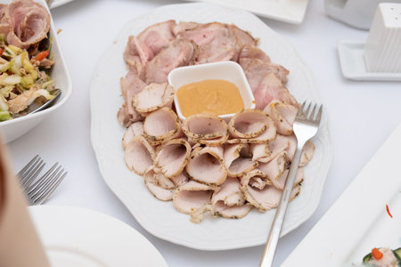 thinly sliced ham arranged on white plate