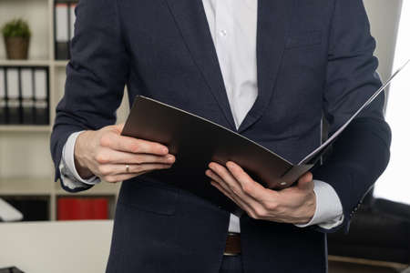Businessman holding a book, dark backgroundの写真素材