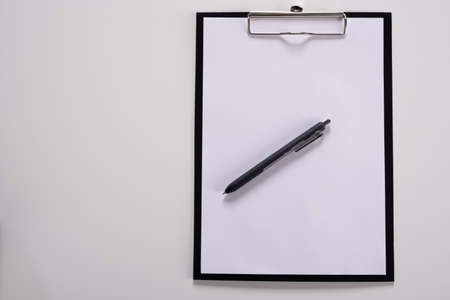 Tablet with writing paper with pen on white tableの写真素材