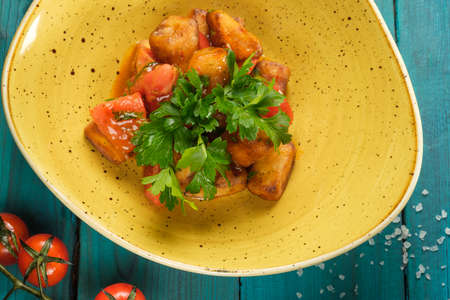 Pieces of baked pumpkin in a yellow plate decorated with parsley leaves standing on a wooden blue tableの写真素材