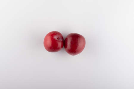Juicy red plums with leaves, isolated on white background.の写真素材