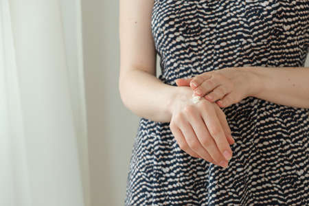  Hand cream. Female hands hold a jar of cream and apply it on hands. Home hand care.の写真素材