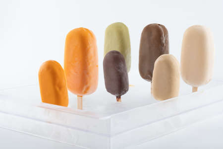 a set of hand-made organic ice cream on sticks of different taste, color and size, covered with a sweet glaze with chocolate, pistachio, Carmel and mango flavors close-upの写真素材